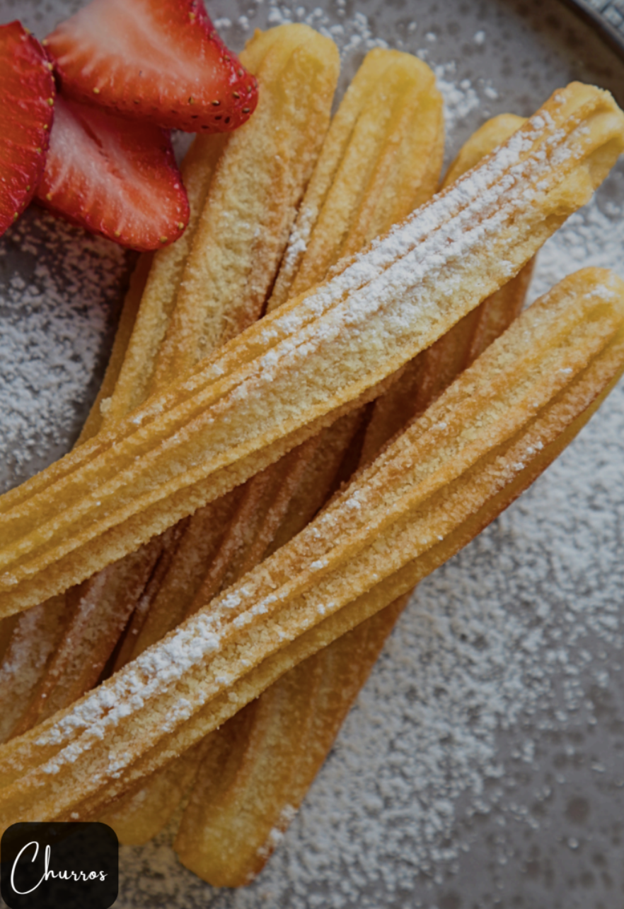 Golden churros with powdered sugar and strawberries